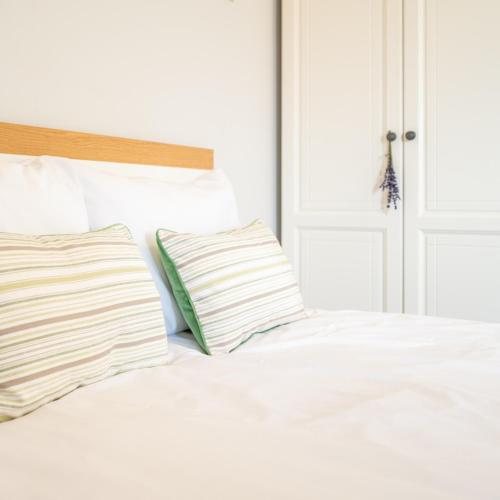 a white bed with two pillows next to a door at Hotel Rozmaryn i Lawenda in Minikowo