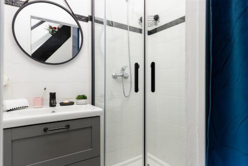 une salle de bain avec une douche, un lavabo et un miroir dans l'établissement - Le P'tit nid -, à Libourne