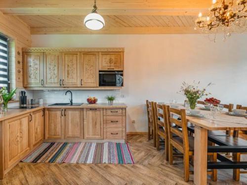 a kitchen with wooden cabinets and a table with chairs at Apartamenty Bąkowo Chatka in Witów