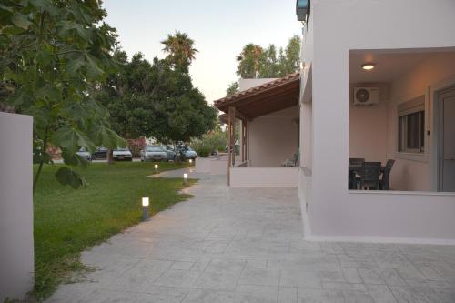 a walkway next to a house with a yard at Philippos & Alexandros Apartments in Tigaki