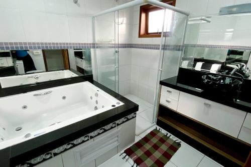 a bathroom with a tub and a sink and a mirror at OPEN HOUSE VARGAS in Sao Paulo