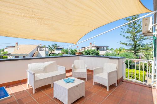 un patio con sedie, tavolo e ombrellone di Villa Arvilla with Private POOL a Campofelice di Roccella
