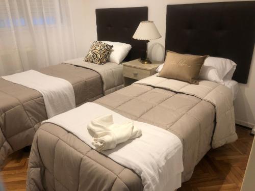 una camera con due letti con lenzuola bianche di Cómodo y cálido a Buenos Aires