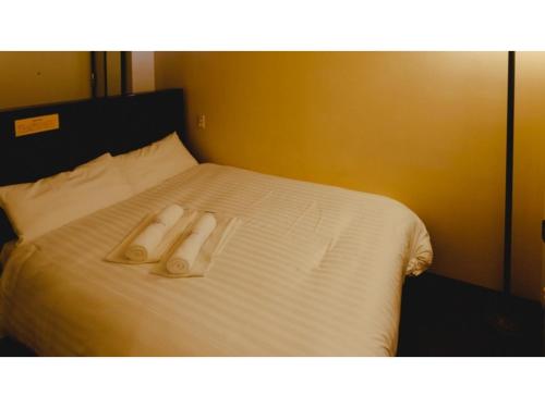 VAN CORTLANDT HOTEL - Vacation STAY 17475v في Aira: سرير وفوط بيضاء فوقه