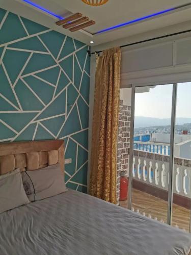 a bedroom with a bed and a large window at Appartement aboubakr ahayek in Chefchaouen