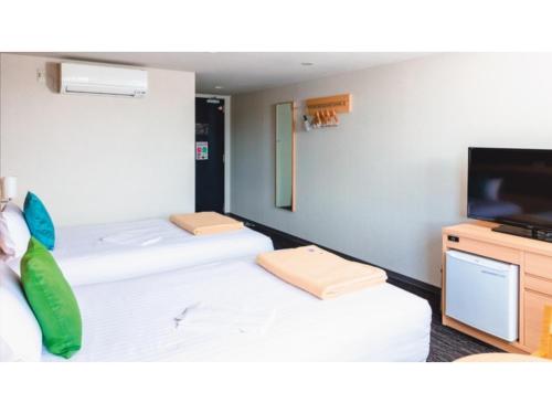 a room with two beds and a flat screen tv at AIRAIKU HOTEL Kagoshima - Vacation STAY 17451v in Aira