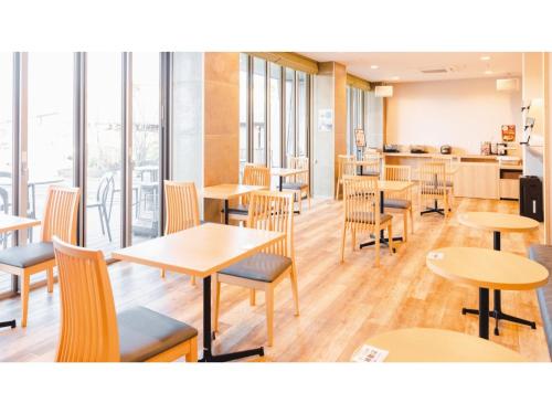 un restaurante con mesas y sillas de madera y ventanas en AIRAIKU HOTEL Kagoshima - Vacation STAY 17424v, en Aira