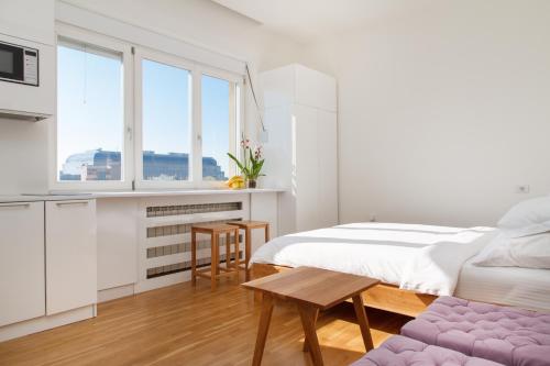 a white bedroom with a bed and a table at Apartment Slavia District in Belgrade