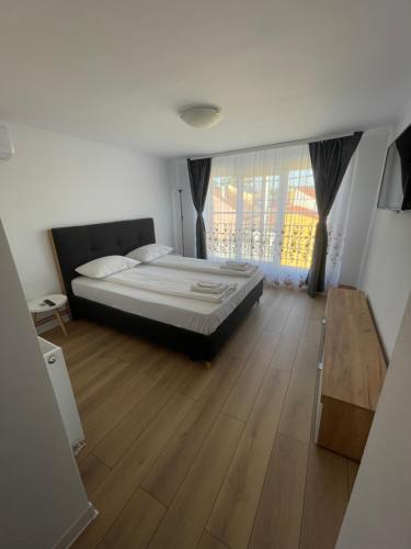 a bedroom with a bed and a wooden floor at Paula Apartment & Rooms in Oradea