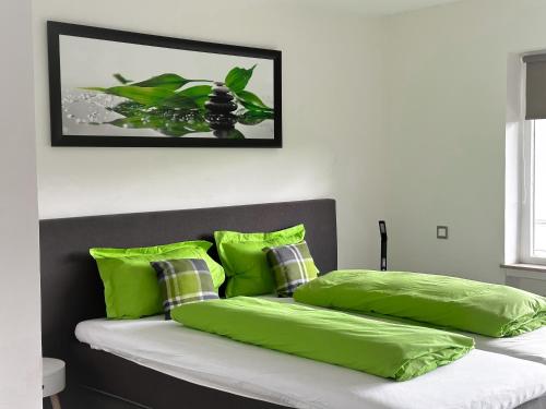 a bed with lime green pillows and a picture on the wall at Gästehotel Lucendi Premium Lounge in Hohenleimbach