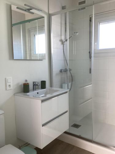 ein weißes Bad mit einem Waschbecken und einer Dusche in der Unterkunft Ker LN in Saint-Nazaire