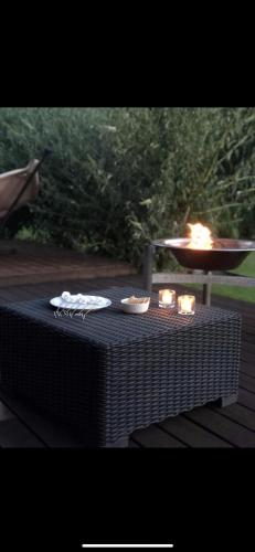 a table with candles on it with a fire in a grill at Dejlig sommerhus 150m fra privat strand in Brenderup