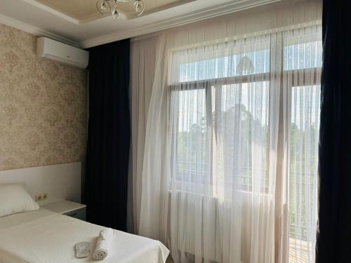 a bedroom with a bed and a window with curtains at House in Tsikhisdziri in K'obulet'i