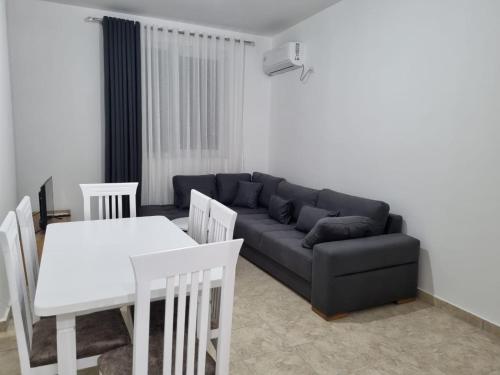 ein Wohnzimmer mit einem Sofa, einem Tisch und Stühlen in der Unterkunft Apartamente Kune Shengjin in Lezha