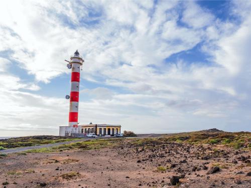 a red and white lighthouse on a hill with a building at Live el Poris chinchorro in Poris de Abona