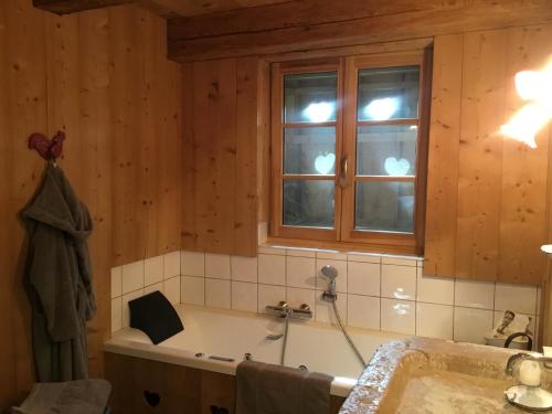 a bathroom with a bath tub and a window at La Chabraque in Le Barboux