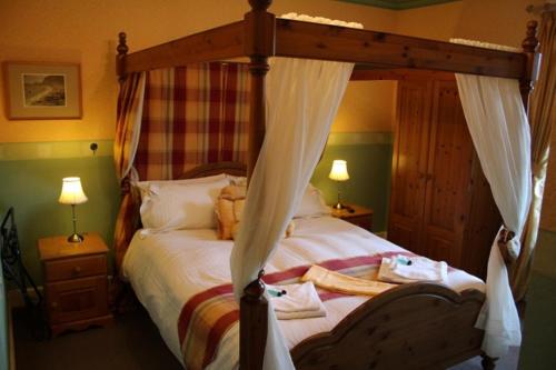 a bedroom with a bed with a wooden canopy at Highland House Callander in Callander