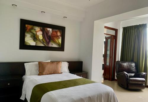 a bedroom with a bed and a leather chair at Serenity Suites Casa Boutique in Bucaramanga