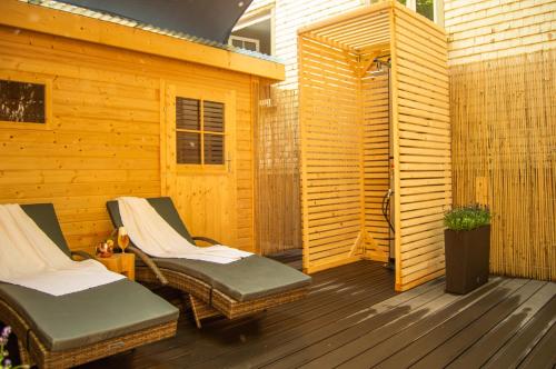a wooden deck with two chairs and a fence at Wellness mitten in der Wasserfallstadt Triberg in Triberg