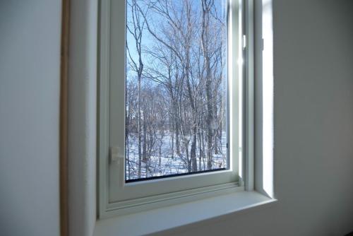 una ventana con vistas a un bosque cubierto de nieve en HOTEL BOTH - Vacation STAY 90935v, en Shari