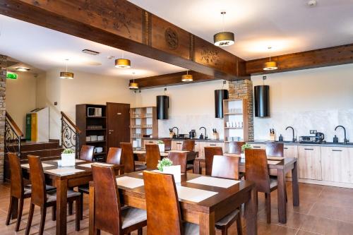 a restaurant with wooden tables and chairs and a kitchen at Willa Szafran in Dzianisz