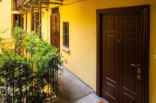 un edificio amarillo con una puerta negra y algunas plantas en Palm Apartment, en Milán