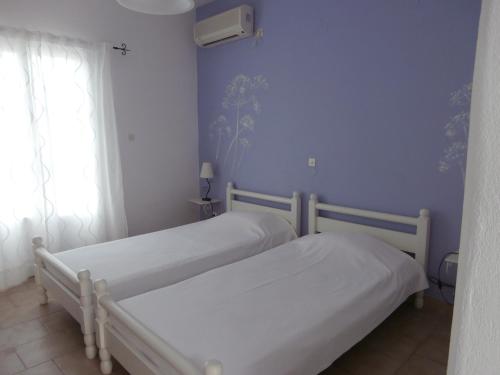 two beds in a bedroom with blue walls and a window at Villa Sophie in Naousa