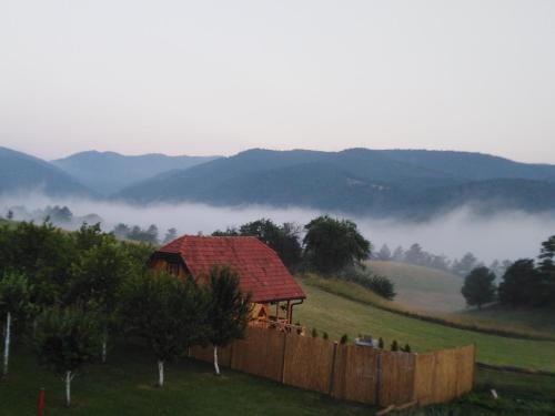 a house on a hill with a fence and fog in a field at Koliba kod Vukašina in Kremna