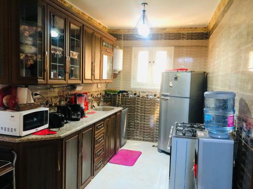 a kitchen with wooden cabinets and a refrigerator at Lovely Villa 5- bedroom with Overflow Pool with Nice Garden at Green Oasis Resort in Alexandria