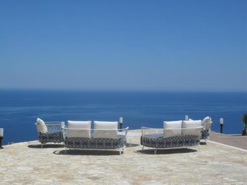 a group of chairs sitting on a patio overlooking the ocean at Hotel Antica Cascina Del Golfo in Scopello