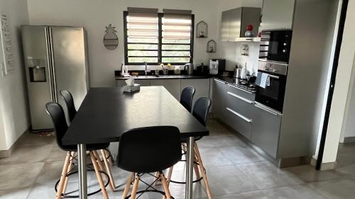 una cocina con mesa negra y sillas en Villa HIMANI, en Saint-Gilles-les-Bains