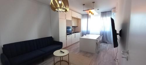 uma sala de estar com um sofá azul e uma cozinha em Modern 1BR apartment with wifi, parking and self check in em Bucareste