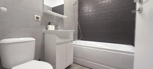 uma casa de banho com um WC branco e uma banheira em Modern 1BR apartment with wifi, parking and self check in em Bucareste