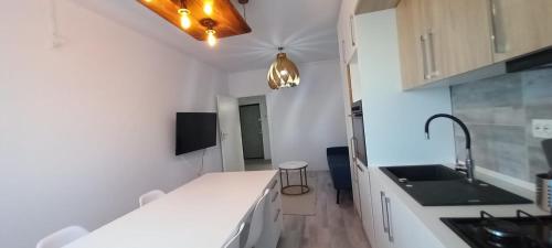 een keuken met witte aanrechtbladen en een wastafel bij Modern 1BR apartment with wifi, parking and self check in in Boekarest