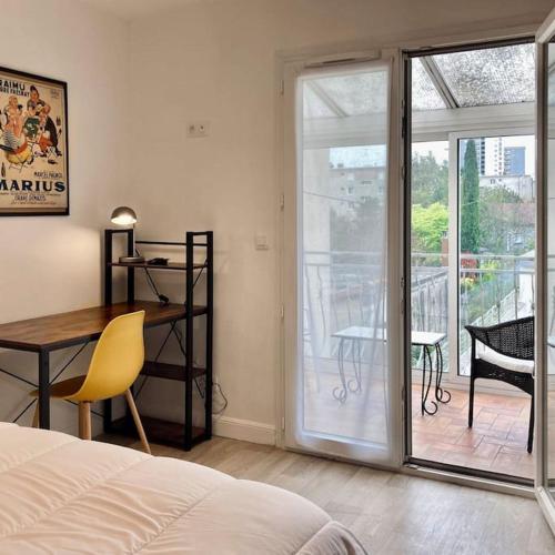une chambre avec un lit et un bureau et un balcon dans l'établissement Magnifique maison classée 3 étoiles, 7 chambres, 5 salles de bain, parking privé, Tarbes ville, à Tarbes