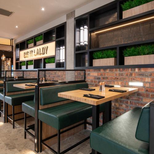 a restaurant with green chairs and tables and a brick wall at Sandman Signature Glasgow Hotel in Glasgow