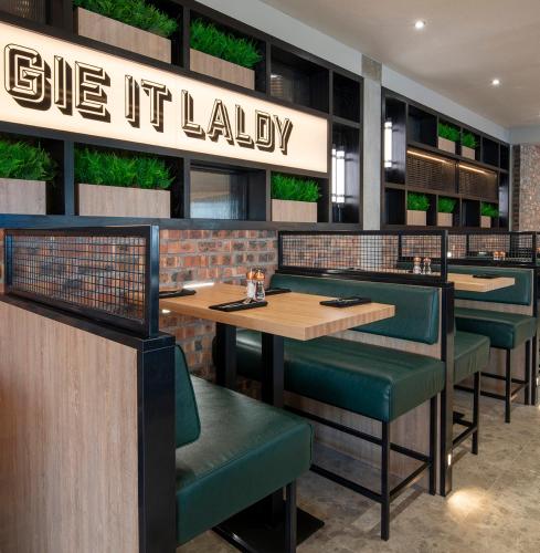 a restaurant with wooden tables and green chairs at Sandman Signature Glasgow Hotel in Glasgow