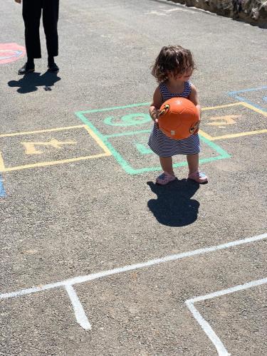 a little girl holding a basketball in a parking lot at Harmony Resort in Tsaghkadzor