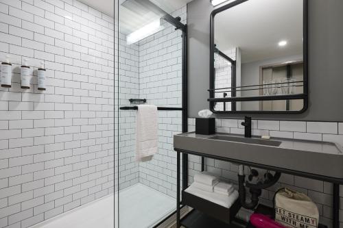 La salle de bains est pourvue d'un lavabo et d'une douche en verre. dans l'établissement Moxy Charleston Downtown, à Charleston