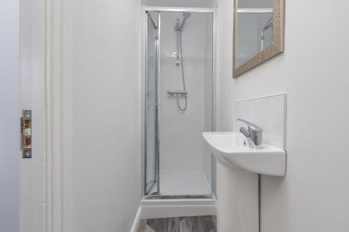 a white bathroom with a sink and a shower at 54 Central in Blackpool