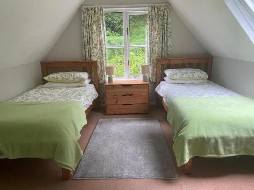 a attic bedroom with two beds and a window at Watermill Cottages - 18th Century converted Mill 10 mins from beach in Dartmouth