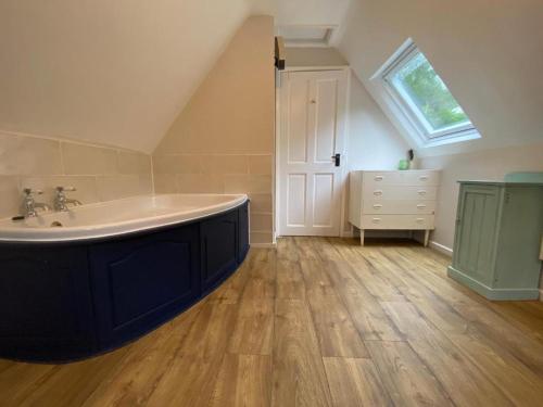 a bathroom with a large bath tub in a attic at Watermill Cottages - 18th Century converted Mill 10 mins from beach in Dartmouth