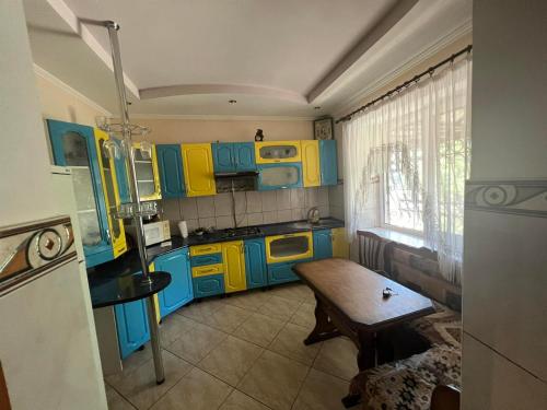 a kitchen with blue and yellow cabinets and a table at Гостевой дом in Ciorescu