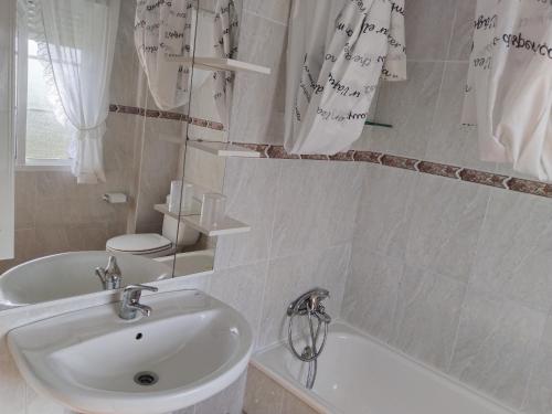 y baño con lavabo, bañera y aseo. en Casa Los Geranios, en Pontevedra