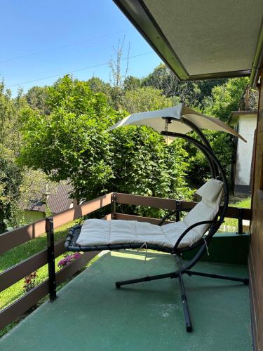 a chair sitting on a porch with an umbrella at Forest paradise in Koprivnica