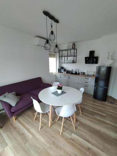 ein Wohnzimmer mit einem Tisch und einem lila Sofa in der Unterkunft Apartament Gąski/Paprotno7 in Gąski