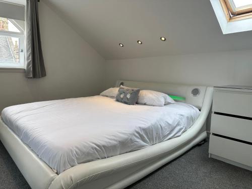 a white bed in a room with a window at Seaside Home in Ardeer Square