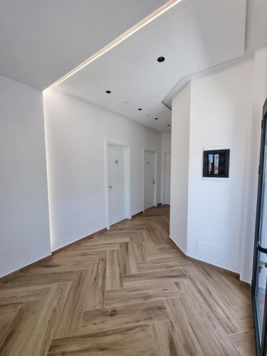 an empty room with white walls and wood floors at White Villa in Përmet