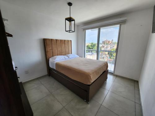 ein Schlafzimmer mit einem Bett und einem großen Fenster in der Unterkunft Nuevo y amplio departamento con alberca y seguridad en el centro de Guadalajara in Guadalajara