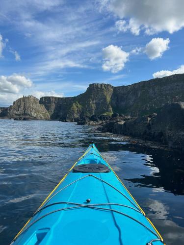 a kayak on the water with mountains in the background at Bayview Farm Holiday Cottages in Bushmills